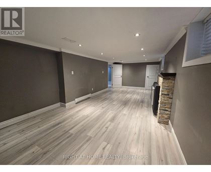 A room with wooden flooring and a stone fireplace.