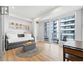 A bedroom with a large bed and a balcony with a chair.