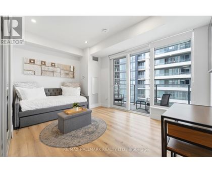 A bedroom with a large bed and a balcony with a chair.