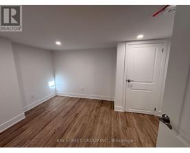 A room with a white door and wooden flooring.