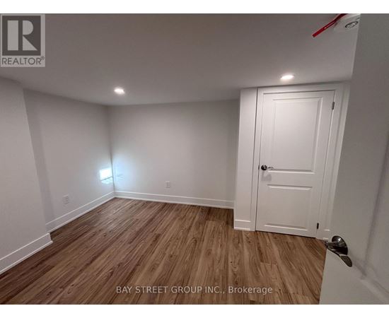 A room with a white door and wooden flooring.