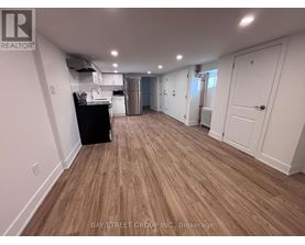 A spacious room with wooden flooring and white walls.