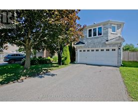 A two-story house with a garage is situated on a street with a tree in front of it.