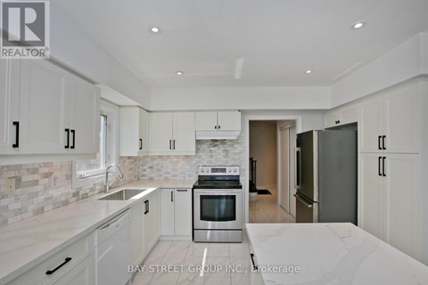 A modern kitchen with white cabinets and a marble countertop.