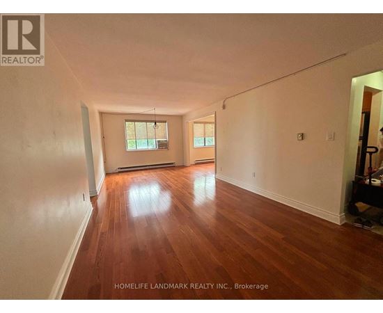 A room with wooden floors and white walls, with a window and a door visible.