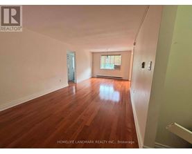 A room with wooden floors and a window is for sale.