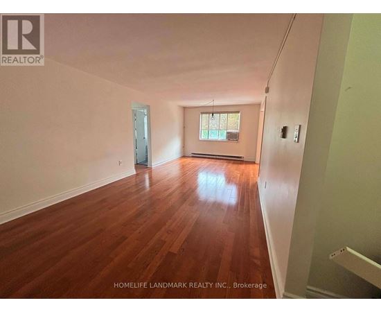 A room with wooden floors and a window is for sale.