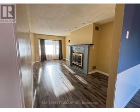 A spacious room with a fireplace and wood flooring.