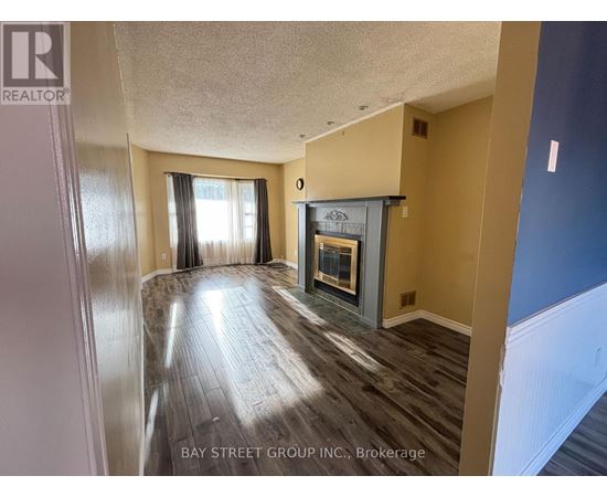 A spacious room with a fireplace and wood flooring.