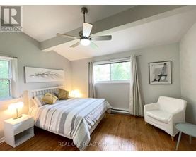 A bedroom with a bed, chair, and ceiling fan.