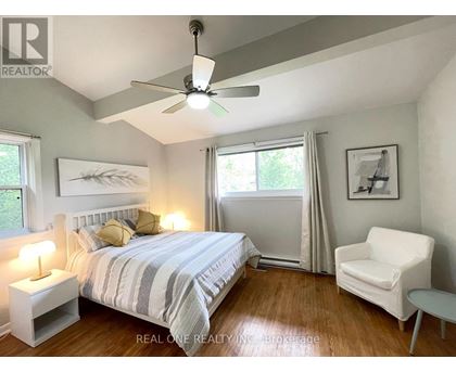 A bedroom with a bed, chair, and ceiling fan.