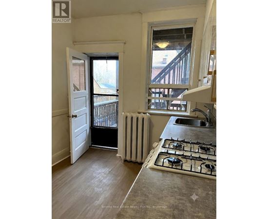 A kitchen with a stove, sink and a window.