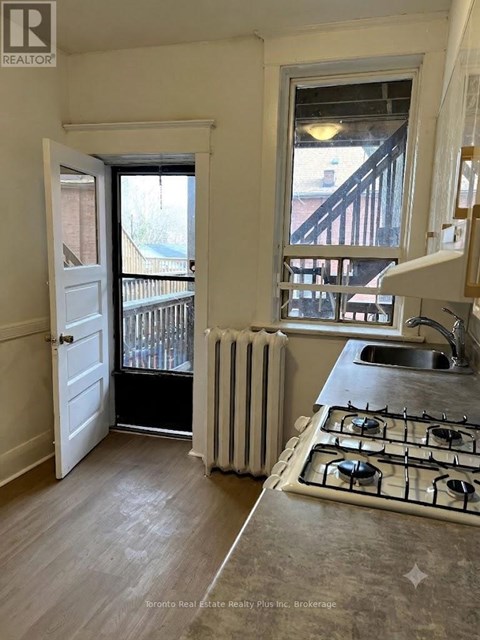 A kitchen with a stove, sink and a window.