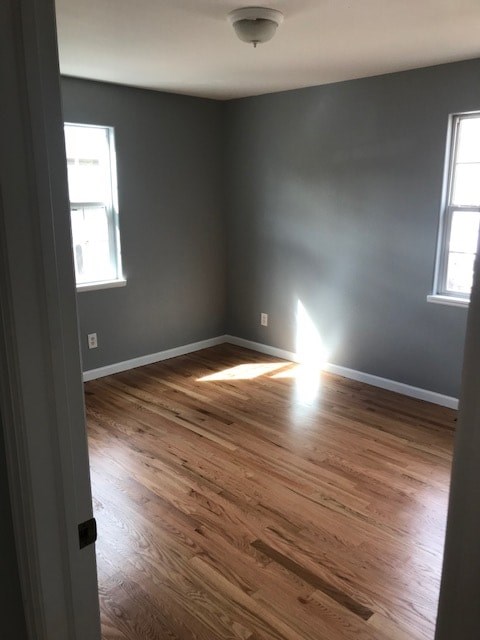 A room with wooden floors and two windows.