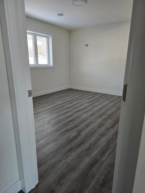 A room with a window and wooden flooring.