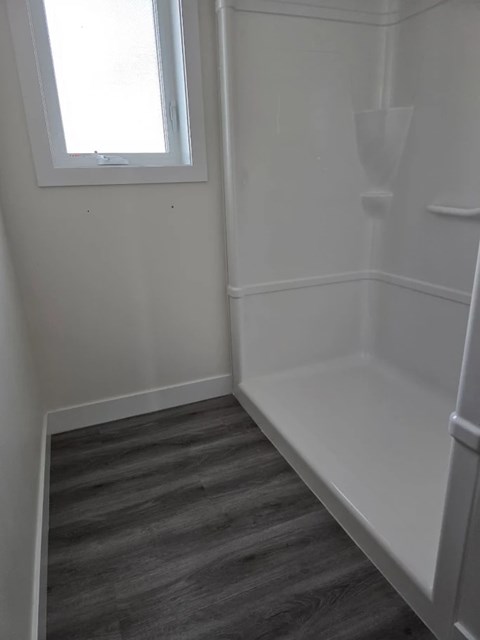 A white bathroom with a window and a white toilet.