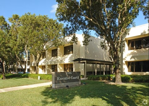 The Executive Court building is surrounded by trees and has a clear blue sky above.