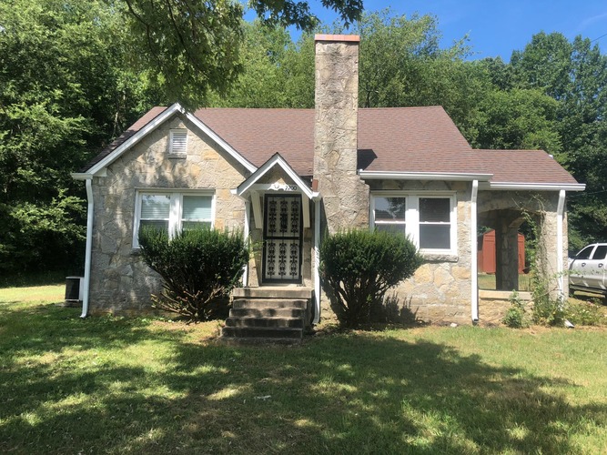 A house with a brown roof and a stone chimney.