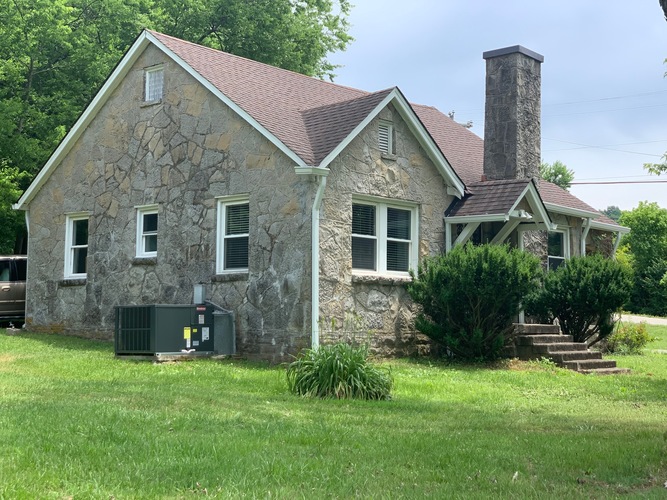 A house with a stone wall and a chimney.