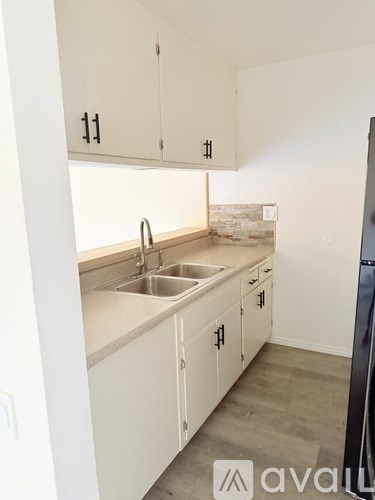 A kitchen with white cabinets and a black fridge.