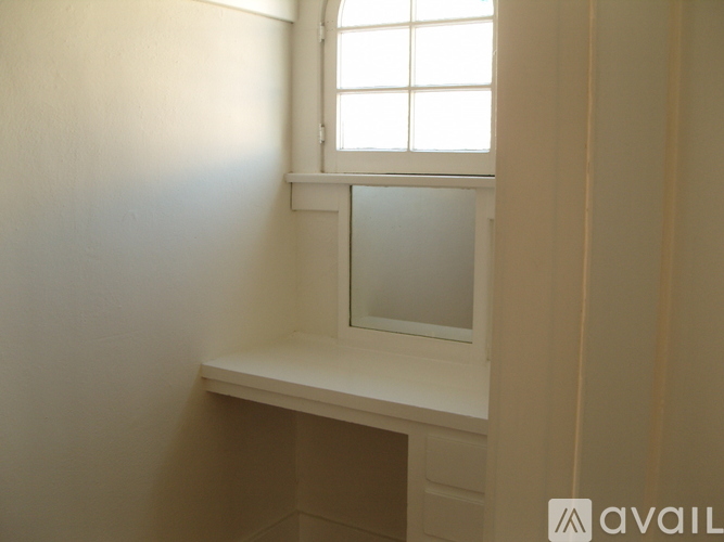 A window with a white frame is in a room with white walls.