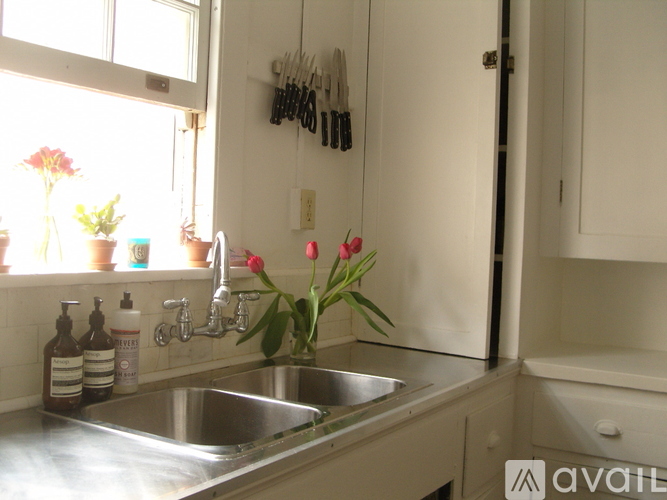 A kitchen sink with a window above it and a bunch of tulips in the foreground.
