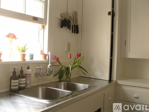 A kitchen sink with a window above it and a bunch of tulips in the foreground.