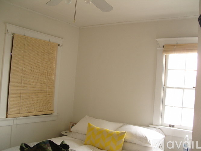 A bedroom with a bed, pillows, and a window with blinds.