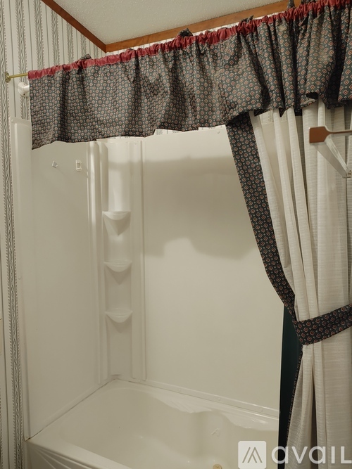 A white bathtub with a shower curtain and a red border.