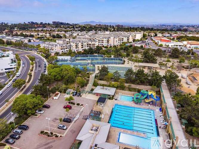 A view of a swimming pool and a parking lot from a high vantage point.