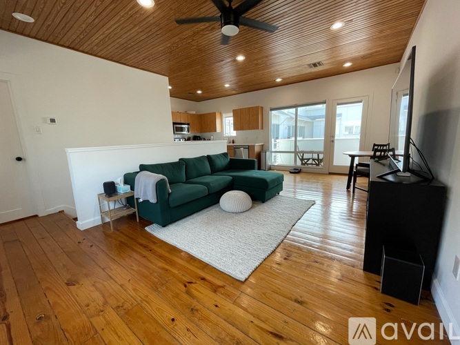 A living room with a green couch and a white rug.