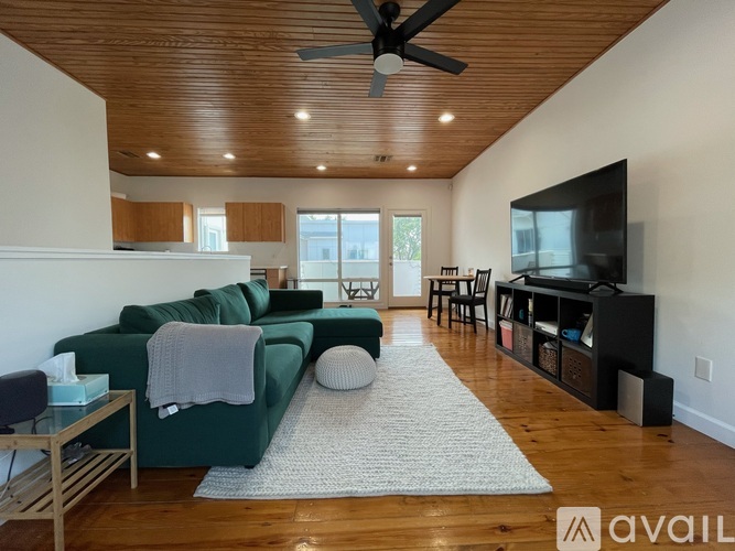 A living room with a green couch and a wooden ceiling.