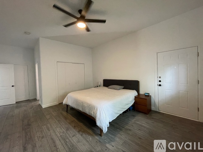 A bedroom with a bed, a ceiling fan, and a nightstand.