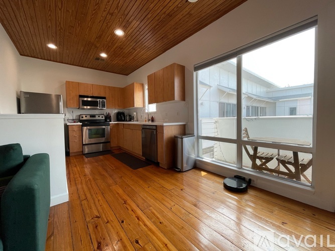 A modern kitchen with wooden floors and a green couch.