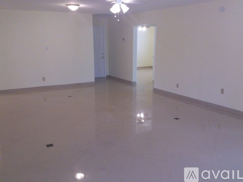 A spacious room with a ceiling fan and two doors.