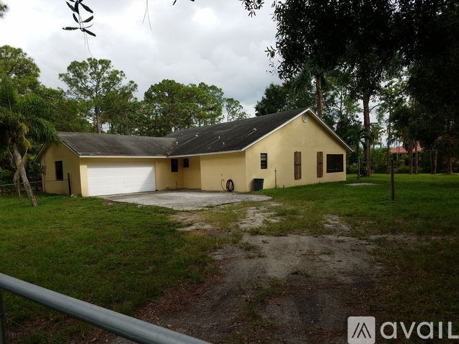 A house with a garage is surrounded by trees and grass.