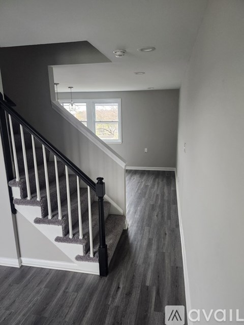A staircase with a black railing and wooden steps leading to a window.