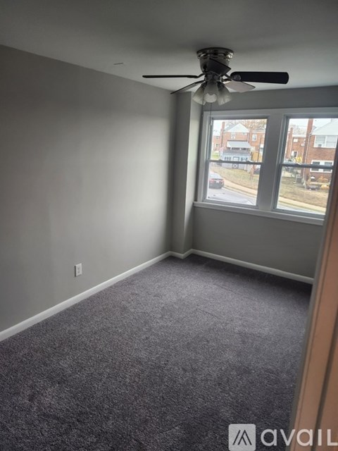 A room with a ceiling fan and a window overlooking a street.