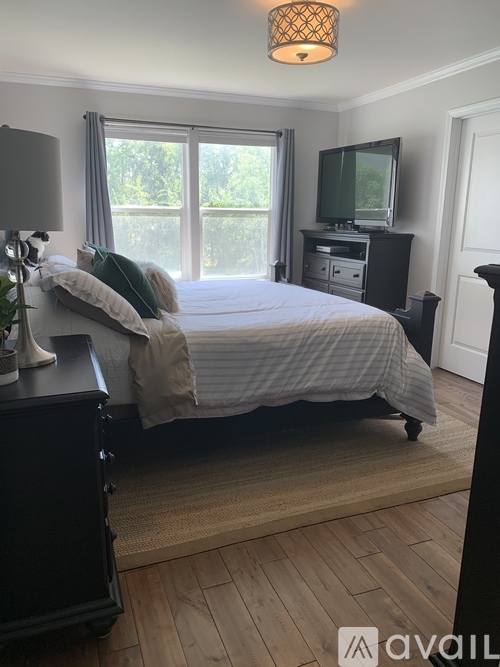 A bedroom with a bed, nightstand, and television.