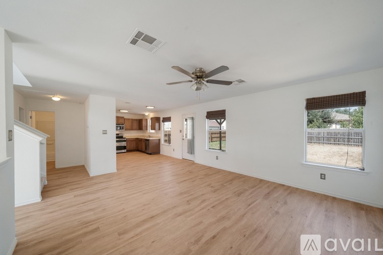 A spacious living room with wooden floors and a ceiling fan.