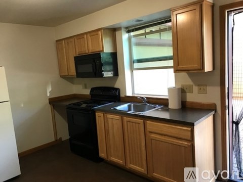 A kitchen with wooden cabinets and black appliances.