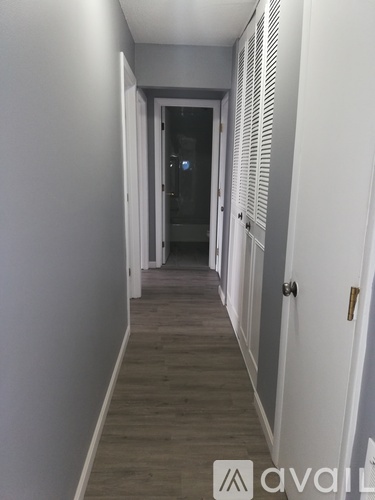 A long hallway with white walls and a wooden floor.