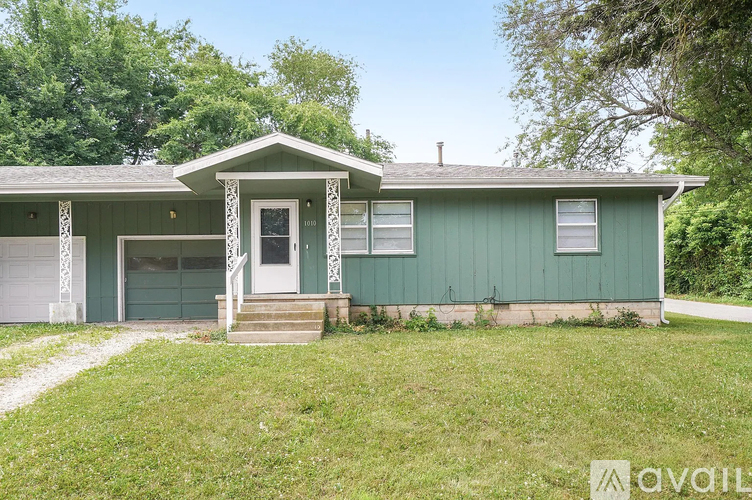 A house with a green exterior and a white door is for sale.