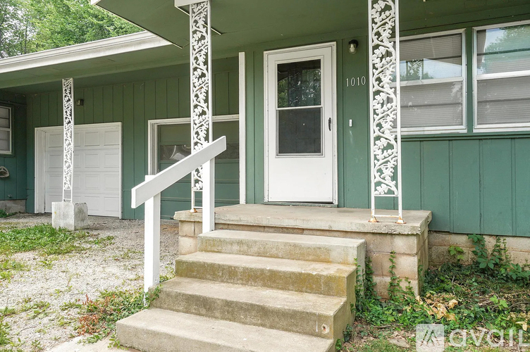 A green house with a white door and steps leading up to it.