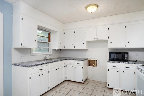 A kitchen with white cabinets and a granite countertop.