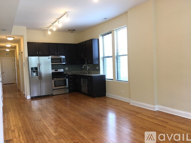 A kitchen with wooden floors and black cabinets.