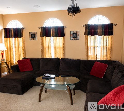 A living room with a black couch and a glass coffee table.