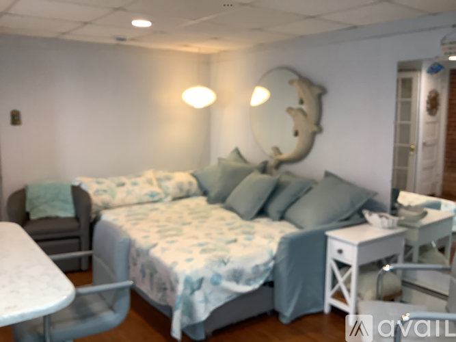 A bedroom with a bed, chair, and a white table.