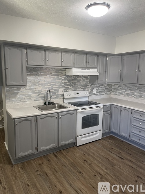 A kitchen with a white countertop and grey cabinets.