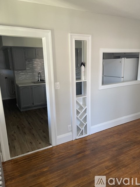 A kitchen with a refrigerator and cabinets is visible through an open door.